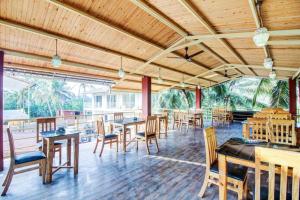een eetkamer met houten tafels en stoelen bij Sea Shell Beach Cottages & Suites in Arambol