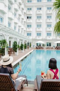 two women sitting in chairs next to a swimming pool at Pearl River Hotel in Hai Phong
