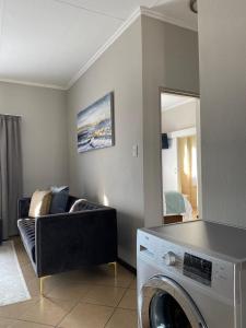 a living room with a washing machine and a couch at Spring Acres Apartment living in Nelspruit