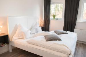a white bed with four pillows on it at Landgasthof Kasch - Hotel und Restaurant in Timmdorf