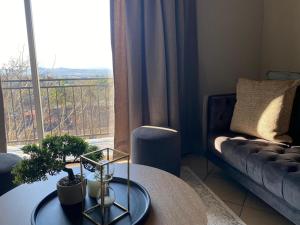 a living room with a table and a couch and a window at Spring Acres Apartment living in Nelspruit