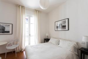 um quarto branco com uma cama e uma cadeira em Brera - Fiori Chiari Charme Apartment em Milão