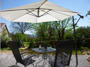 un tavolo e sedie sotto un ombrellone bianco di La Konnet a Rougnat
