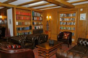 a living room with leather furniture and book shelves at Belle Epoque Hotel Victoria & Apartments in Kandersteg