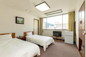 a hotel room with two beds and a television at Itoen Hotel New Sakura in Nikko