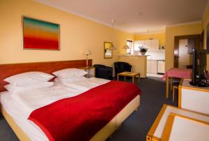um quarto de hotel com uma cama grande e um cobertor vermelho em Kurpark-Residenz Deidesheim em Deidesheim