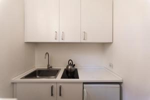 uma cozinha com um lavatório e armários brancos em Brera - Fiori Chiari Charme Apartment em Milão