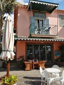 an umbrella and chairs and a table and a building at A Casa Do Caseiro in Funchal