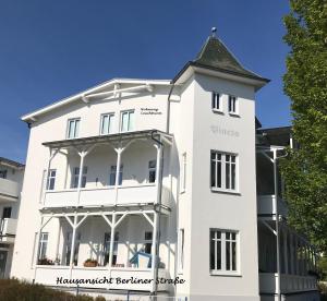 a white building with a clock tower on top at Meerblick Apartments Villa Vineta Göhren in Göhren
