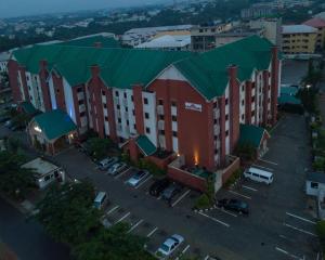 a large building with a green roof in a parking lot at Hawthorn Suites by Wyndham Abuja in Abuja