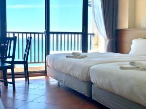 um quarto de hotel com duas camas e uma varanda em Guesthouse High Wave em Yanliau