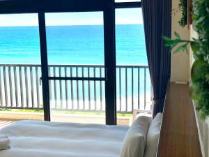 a bedroom with a view of the ocean from a balcony at Guesthouse High Wave in Yanliau
