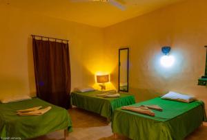 Habitación con 2 camas verdes y espejo. en Siwa Shali Resort en Siwa