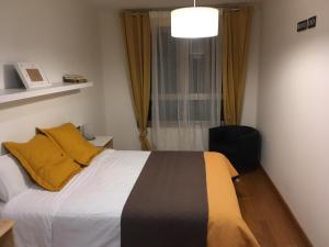 a bedroom with a bed with yellow pillows and a window at Apartamento Playa Poniente in Gijón