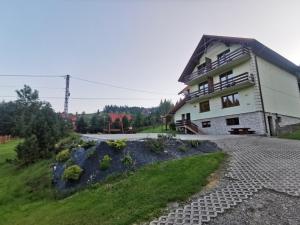 ein Haus auf einem Hügel mit Kieseinfahrt in der Unterkunft Agroturystyka u Beaty Dom II in Korbielów