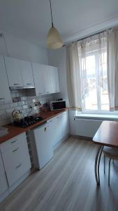 a kitchen with white cabinets and a table and a window at Stara Kamienica Centrum in Mrągowo