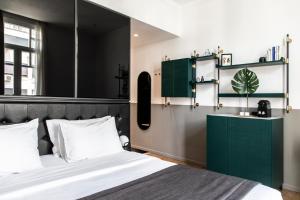 a bedroom with a bed with a green headboard and a mirror at The Modernist Thessaloniki in Thessaloniki