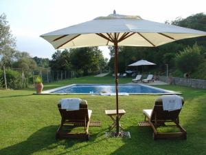 dos sillas y una sombrilla junto a una piscina en Can Serola, en Sales del Llierca
