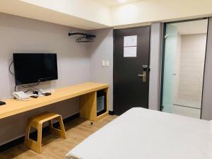 台北的住宿－晴悅旅店，客房设有一张桌子、一台电视和一张床