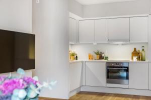 a white kitchen with white cabinets and a tv at Frogner House Apartments - Huitfeldtsgate 19 in Oslo