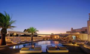 a resort with a pool with lounge chairs and palm trees at Andronikos Hotel in Mýkonos City