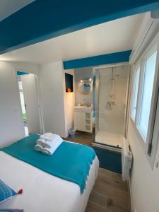 a bedroom with a bed and a bathroom with a shower at Maisonnette de la mer in Hermanville-sur-Mer