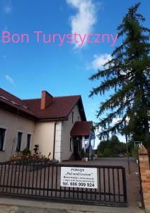 a sign on a fence in front of a house at Pensjonat Agroturystyczny Pod Modrzewiem in Florczaki