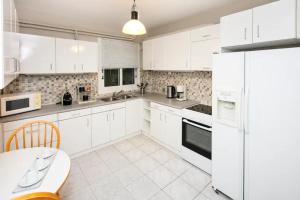 a white kitchen with white appliances and a table at Omirou “Best Kept Secret” in Athens