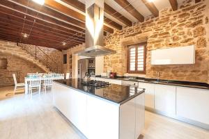 - une cuisine avec un mur en pierre et une cuisinière four supérieur dans l'établissement Casa Sa Pedra, en el centro histórico de Alcudia, à Alcúdia