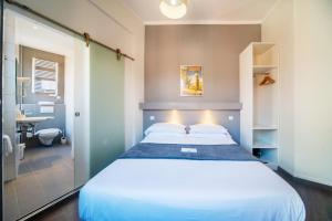 a bedroom with a large white bed and a bathroom at Residence Metropole Toulouse in Toulouse