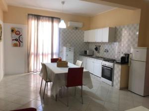 cocina con mesa con sillas y cocina con electrodomésticos blancos en Casa Vacanze Fabrizio en Balestrate