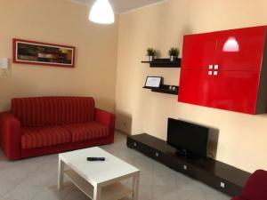 Casa Vacanze Fabrizio في باليستراتي: غرفة معيشة مع أريكة حمراء وتلفزيون
