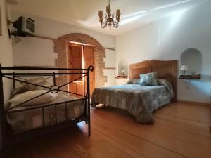 um quarto com uma cama e um lustre em La Aldaba del siglo XX em Alcañizo