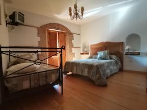Un dormitorio con una cama y una lámpara de araña. en La Aldaba del siglo XX, en Alcañizo