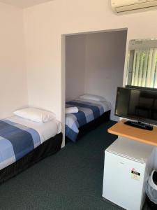 a hotel room with two beds and a flat screen tv at Mount Beauty Motor Inn in Mount Beauty