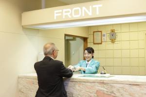 a man and a woman shaking hands at a front counter at Hotel Green Park in Sendai
