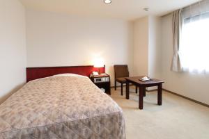 ein Hotelzimmer mit einem Bett, einem Tisch und einem Stuhl in der Unterkunft Hotel Green Park in Sendai