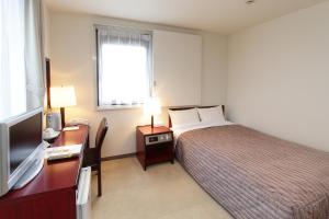 ein Hotelzimmer mit Bett, Schreibtisch und Fernseher in der Unterkunft Hotel Green Park in Sendai + 6 Fotos
