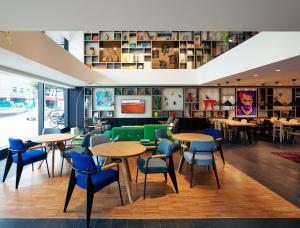 a restaurant with wooden tables and blue chairs at citizenM Kuala Lumpur Bukit Bintang in Kuala Lumpur