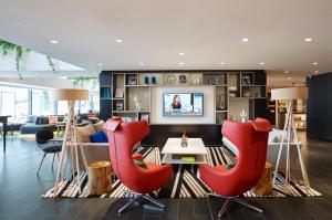 a living room with red chairs and a table at citizenM Kuala Lumpur Bukit Bintang in Kuala Lumpur