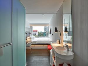 a bathroom with a sink and a bed and a mirror at citizenM Kuala Lumpur Bukit Bintang in Kuala Lumpur +24 photos