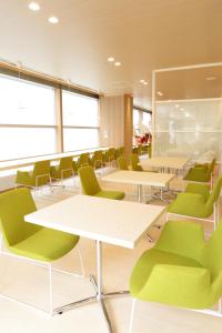 a waiting room with green chairs and tables at Hotel Premium Green Hills in Sendai