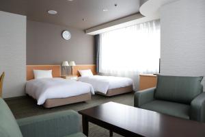 a hotel room with two beds and a couch at Hotel Premium Green Hills in Sendai