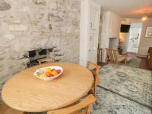 a table with a bowl of fruit in a room with a stone wall at Llawenfan in Criccieth