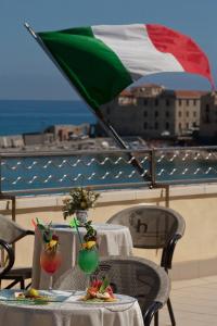 a table with two drinks and an italian flag at Hotel Riva Del Sole in Cefalù