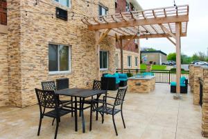 a patio with a table and chairs and a wooden pergola at Clarion Pointe Bettendorf - Quad Cities in Bettendorf