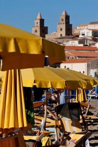 a group of yellow umbrellas and chairs on a beach at Hotel Riva Del Sole in Cefalù