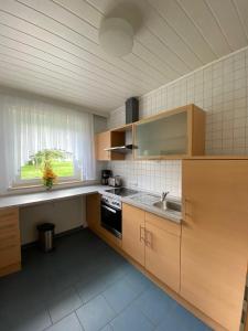 eine Küche mit Holzschränken, einem Waschbecken und einem Fenster in der Unterkunft Gemütliches Appartement - WBS in Goldkronach