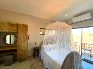 a bedroom with a bed with a mosquito net at Doornkom in Marloth Park
