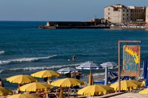 a beach with yellow umbrellas and the ocean at Hotel Riva Del Sole in Cefalù